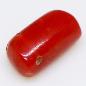 Close-up of a sparkling precious coral loose stone on a white background.