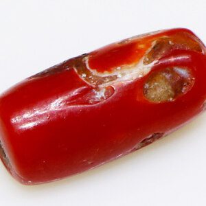 Close-up of a sparkling red coral loose stone on a white background.