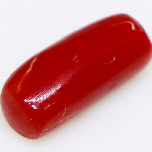 Close-up of a sparkling 5-carat red coral stone on a white background.