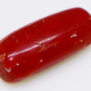 Close-up of a sparkling red coral stone on a white background.