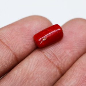 Close-up photo of a red moonga gemstone in hand: Natural red moonga stone showcasing fiery beauty.