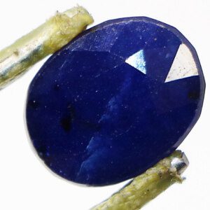 Loose blue sapphire gemstone held in tweezers, a symbol of good fortune.