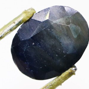 Close-up of a vibrant Neelam ka Pathar (sapphire) held in tweezers.