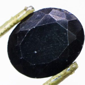 Close-up of a stunning blue sapphire held in tweezers.