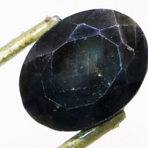 Close-up of a mesmerizing black sapphire held in tweezers.