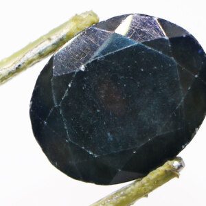 Close-up of teal sapphire loose gemstone with tweezers