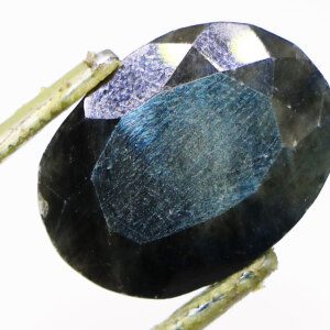 Close-up of opaque sapphire loose gemstone with tweezers