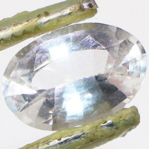 Real Ceylon white topaz gemstone held in tweezers, close-up