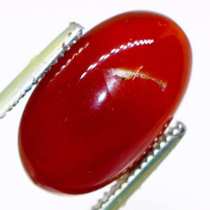 Close-up of a rare and expensive agate gemstone held in tweezers, showcasing its exceptional clarity and vibrant color.