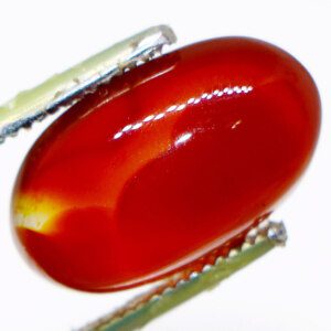 Close-up of a captivating agate loose gemstone held in tweezers, showcasing its vibrant colors and natural beauty.