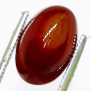 Semi precious Agate gemstone held by tweezers for close inspection