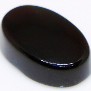 Close-up of Sulemani Black Hakik loose gemstone held in tweezers, showcasing its deep smoky black color.