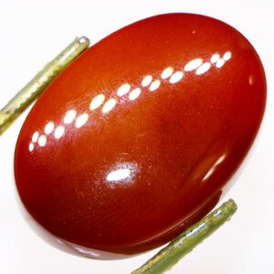 Closeup photo of a Brown Agate loose gemstone held in tweezers, showcasing its rich brown color and banding patterns.